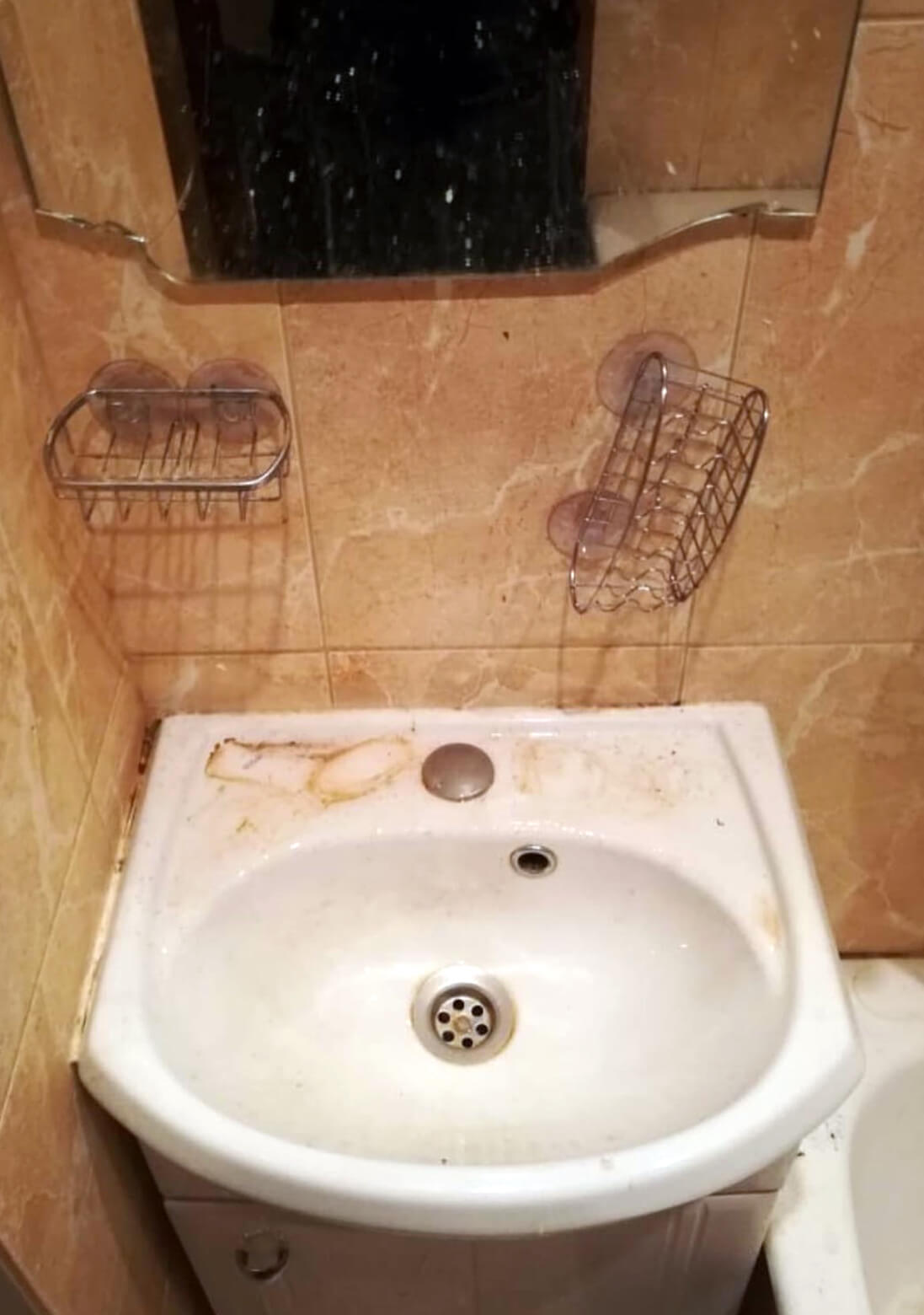 Загрязненная мойка с зеркалом в ванной комнате